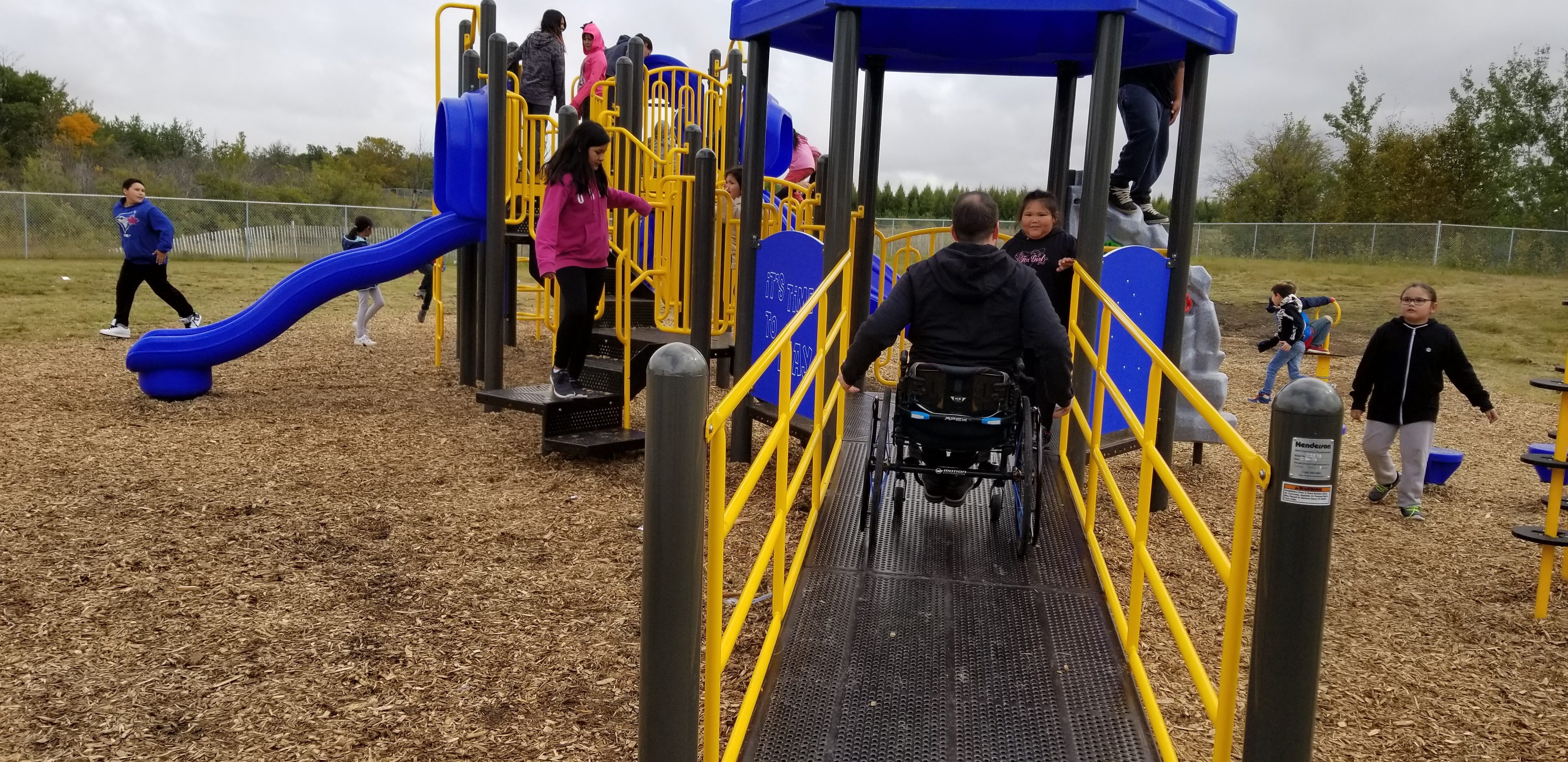Muskoday Accessible Playground Grand Opening 2 man in wheelchair on playground structure ramp