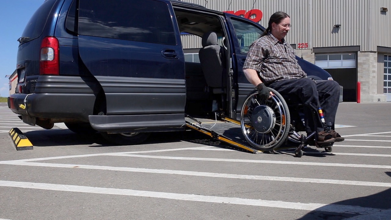 Man using wheelchair exiting minivan ramp